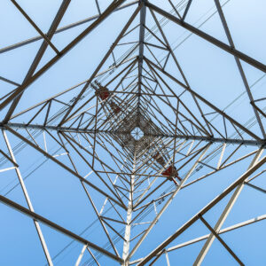 high voltage pylon on blue sky background, upward view of transmission line tower.